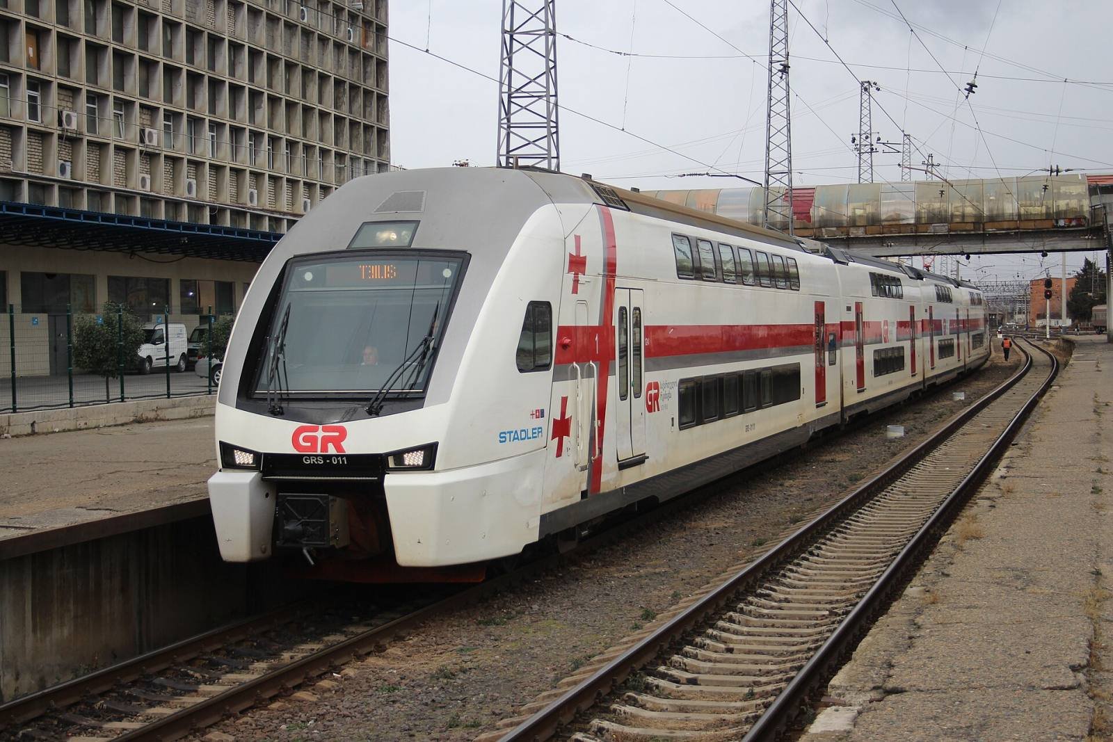 A white and red double-decker Georgian Railway train at a platform in Tbilisi