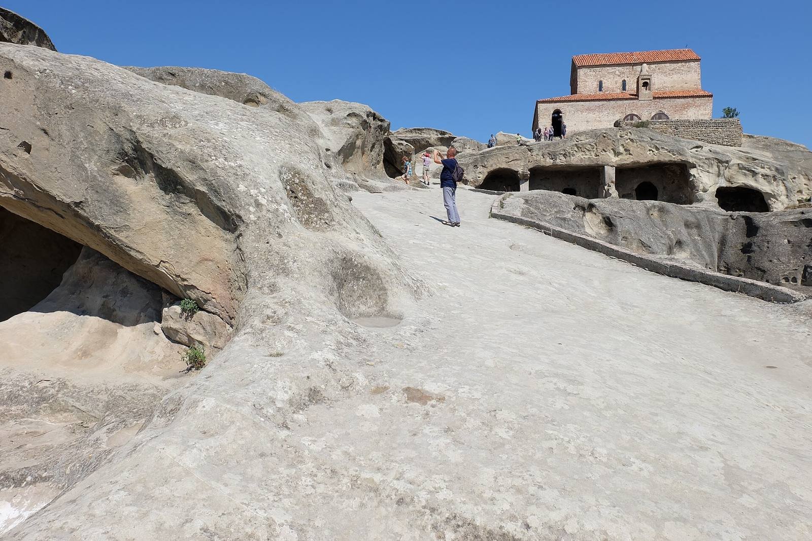 Visitors walking up the rock-cut main street of Uplistsikhe towards the church on top
