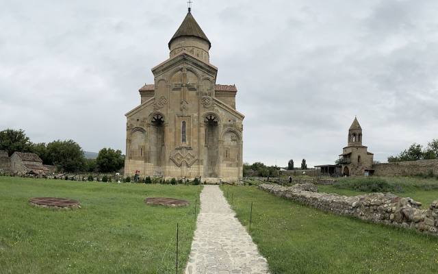 The east façade of Samtavisi Cathedral, with its carved cross and arches, at the end of a stone path