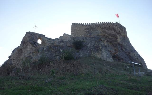 The ruined walls of Surami Fortress on a rocky outcrop above the town
