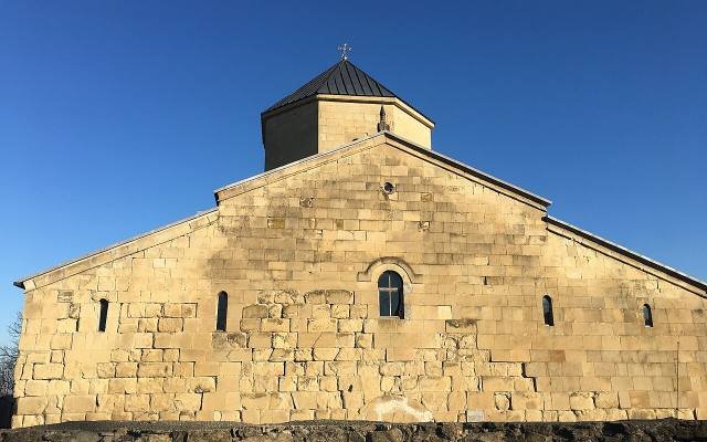 The plain stone walls of Tsromi Church and its low drum against a deep blue sky