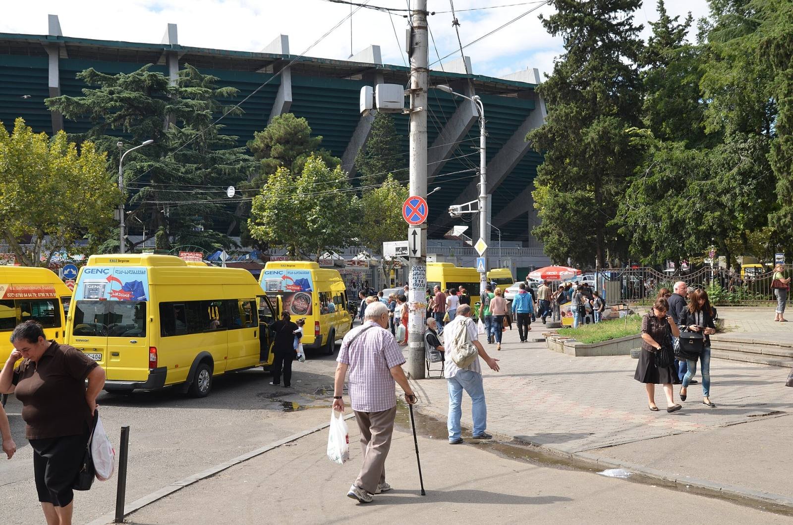 Yellow marshrutka minibuses and passengers at a busy stop in Tbilisi