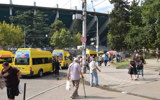 Yellow marshrutka minibuses and passengers at a busy stop in Tbilisi
