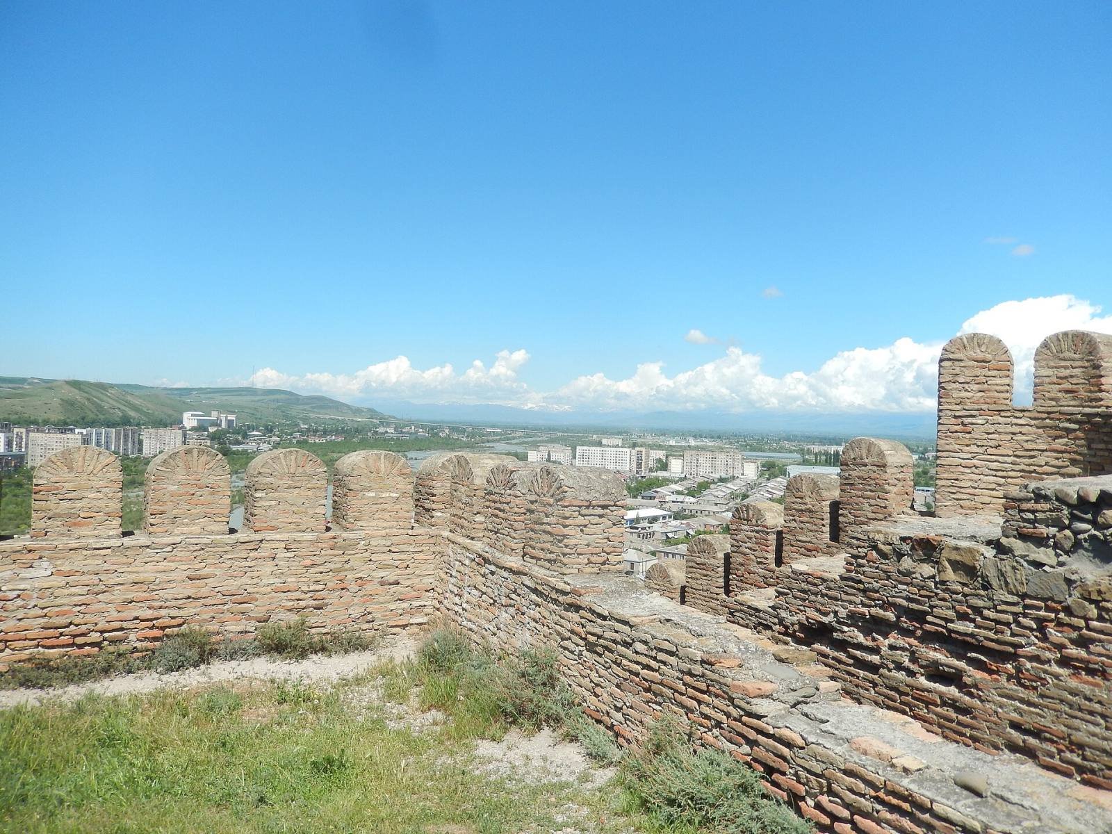 The crenellated walls of Gori Fortress, with the city and green hills beyond