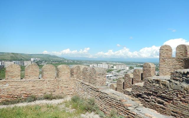 The crenellated walls of Gori Fortress, with the city and green hills beyond