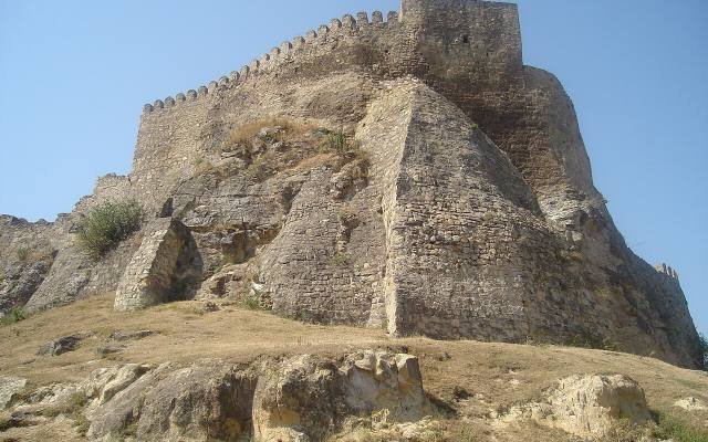 The ruined fortress of Surami on its rocky hill above the trees