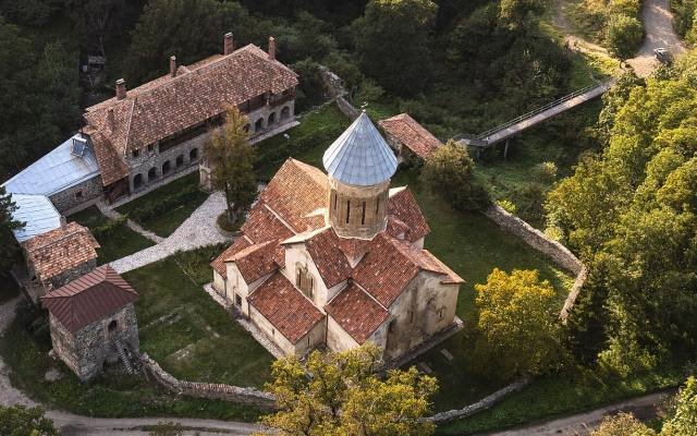Kvatakhevi Monastery with its domed church and red roofs among the trees of its gorge, seen from above
