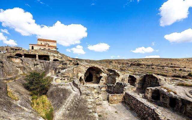 A restored medieval church of brick and stone on top of the rock-cut caves of Uplistsikhe