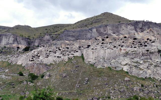 The cave monastery of Vardzia, hundreds of openings cut into a cliff above green slopes