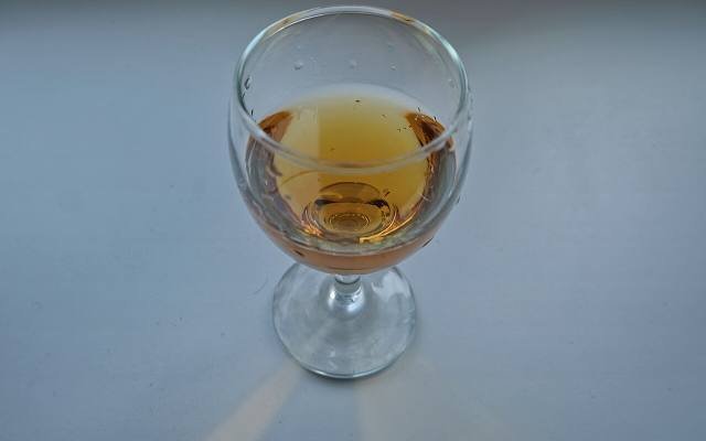 A glass of amber Rkatsiteli wine made in a qvevri clay jar